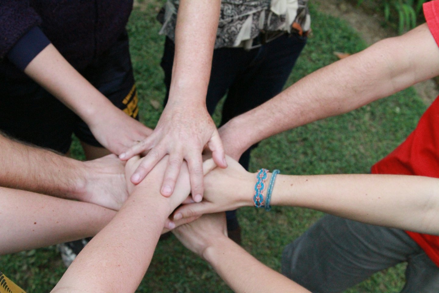 Verschiedene Hände, die als Symbol für Teamwork und Einheit gestapelt sind.